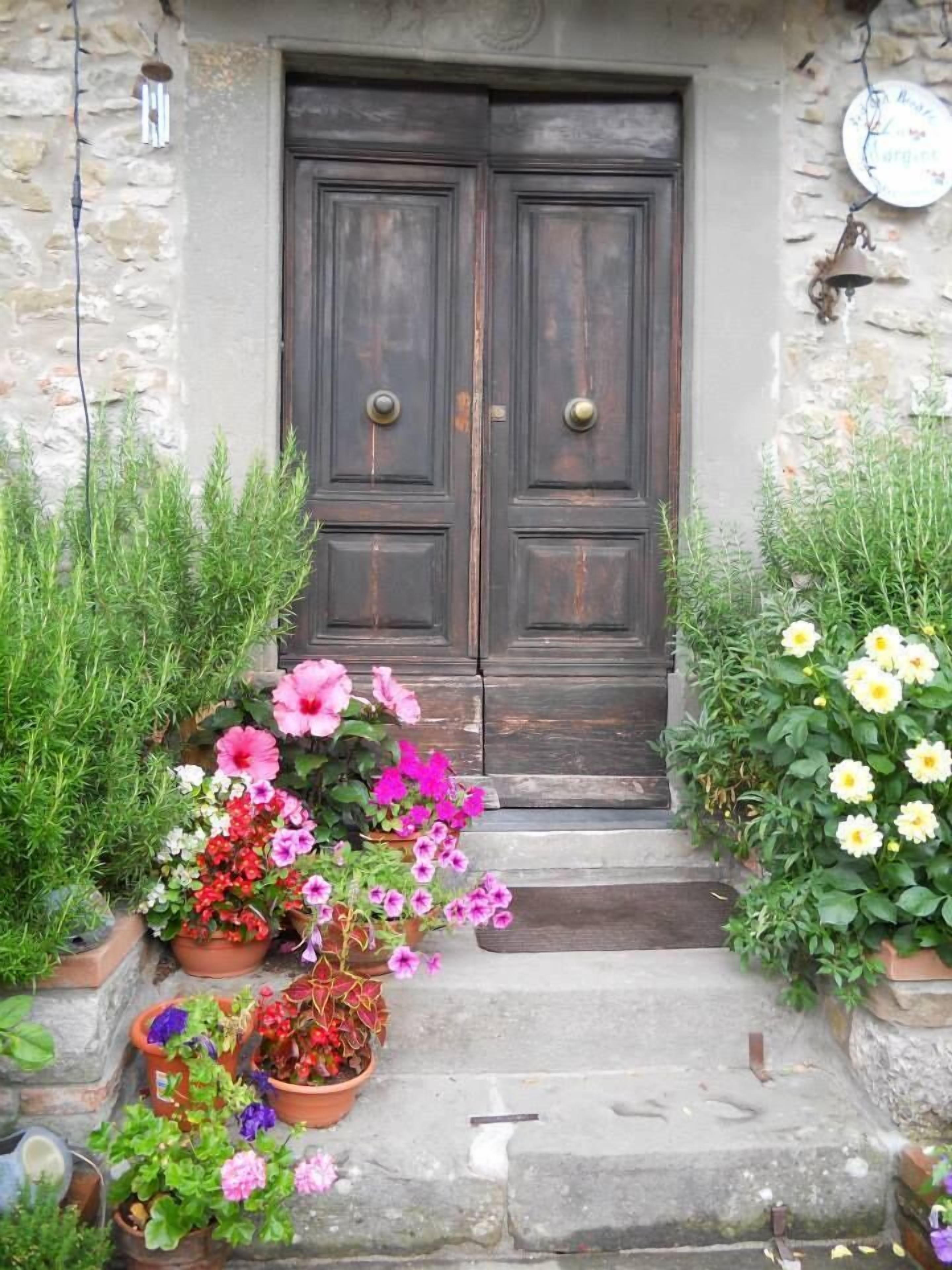 A rustic stone building with a dark wooden double door and a small set of stone steps leading up to it.