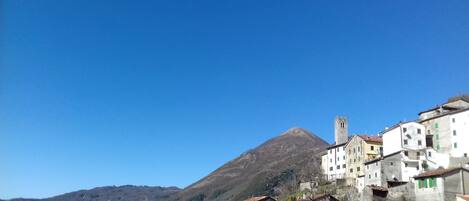 A mountainous landscape with a prominent peak and a cluster of buildings with traditional architecture.