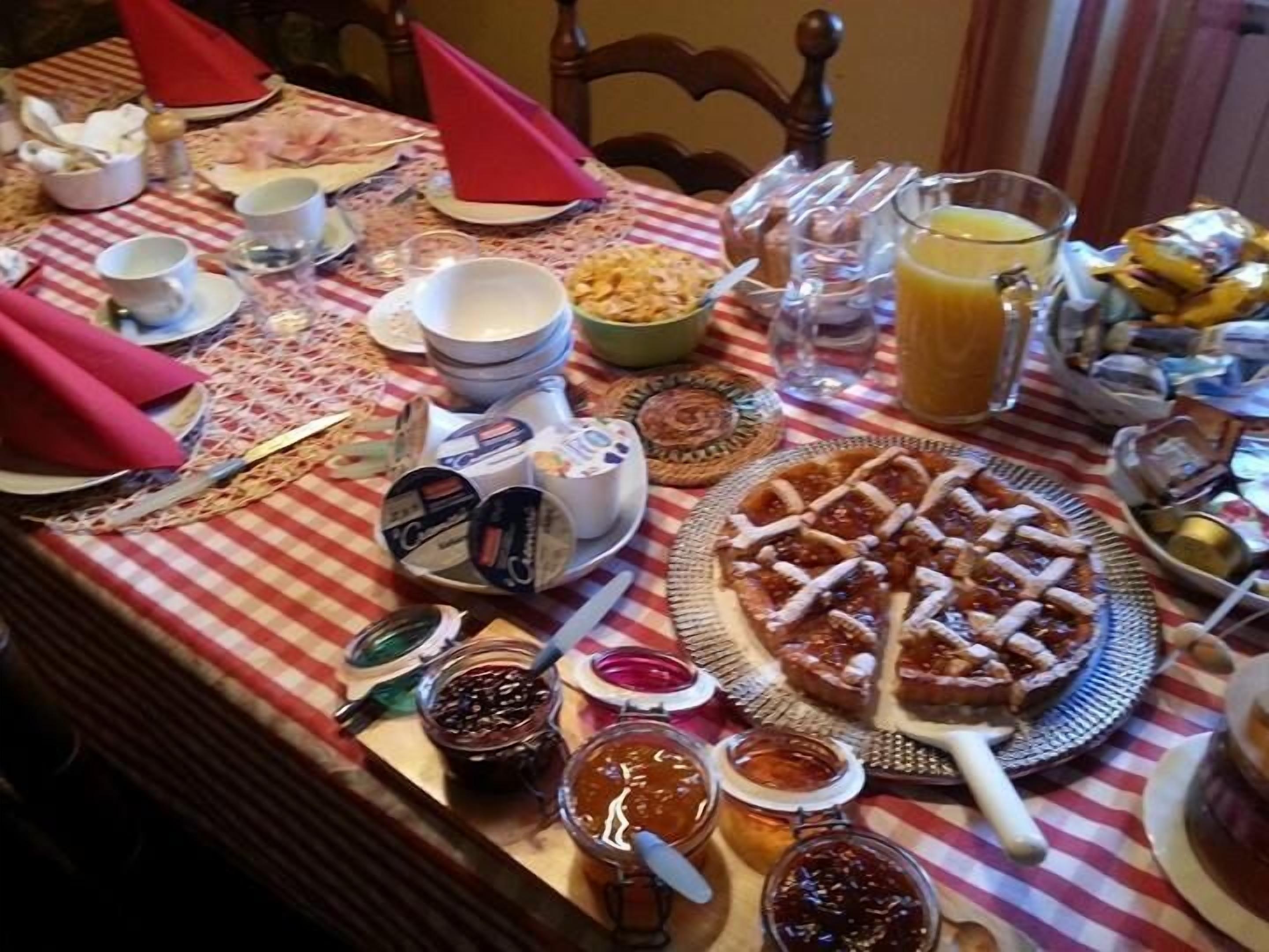 A table set with various food items, including a pie, condiments, and a pitcher of orange juice.