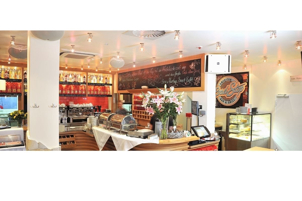 A restaurant with a chalkboard menu, a display case with food items, and a counter with a cash register.