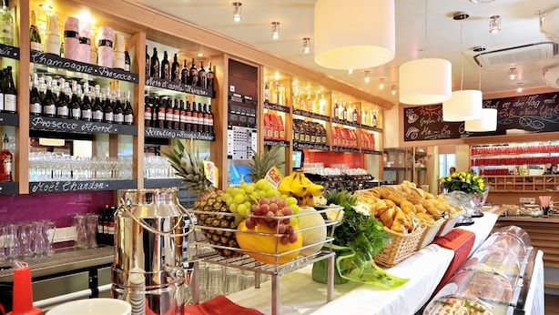 A buffet area with a variety of food items and a selection of wine bottles. - Stadthotel Langenfeld (Langenfeld)