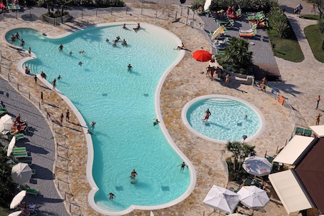 Una piscina al aire libre, sombrillas, sillones reclinables de piscina. Camping Baia Verde