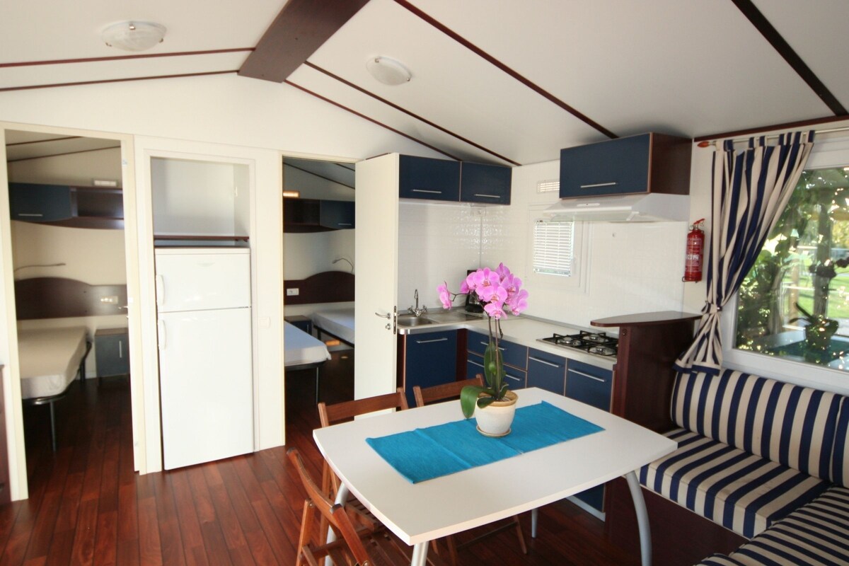 A compact RV kitchen with a dining area, a sink, and a stove.