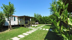 A small, single-story house with a porch and a covered outdoor seating area. - Camping Baia Verde (Manerba del Garda)