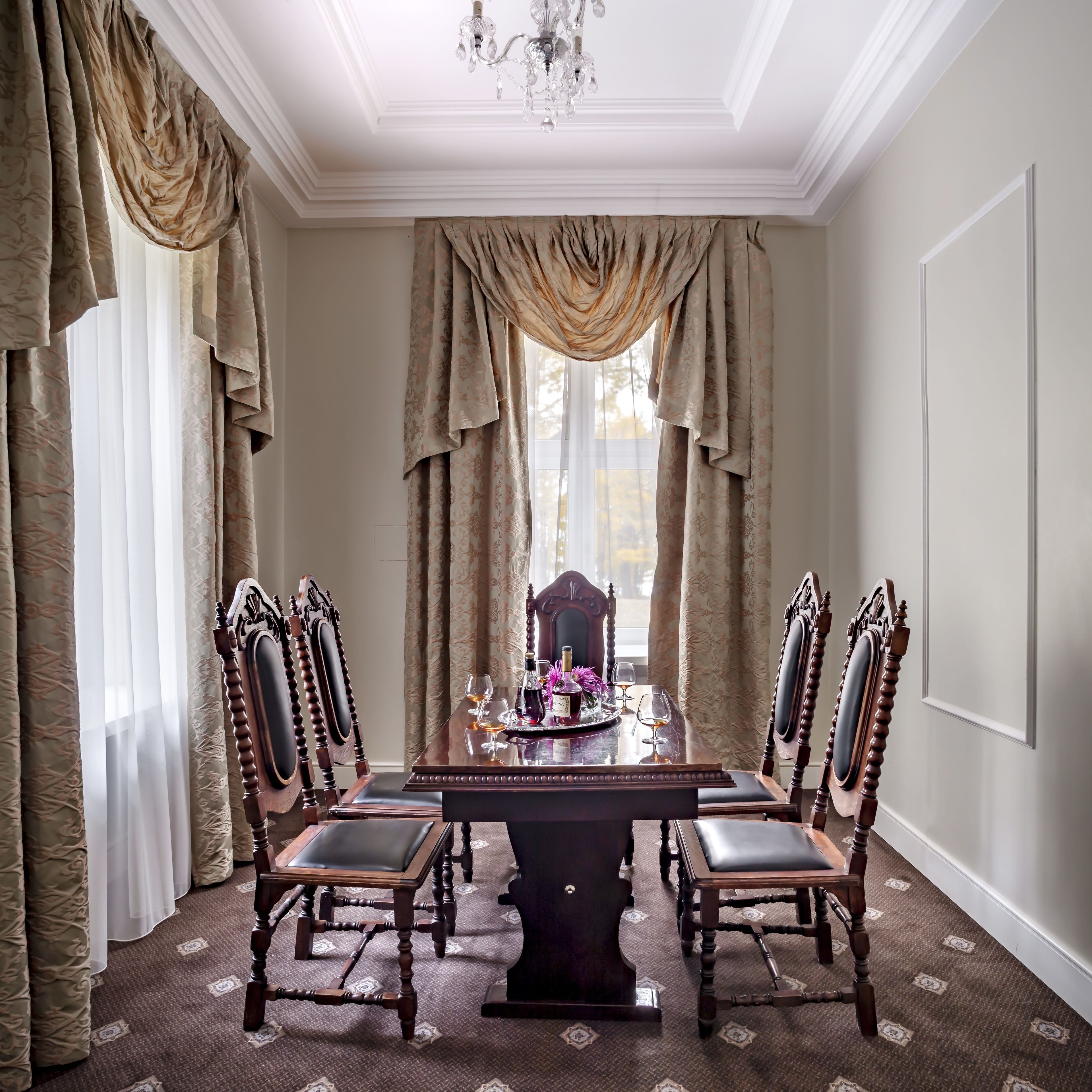 Une salle à manger élégante, avec une longue table, des chaises richement décorées et un lustre.