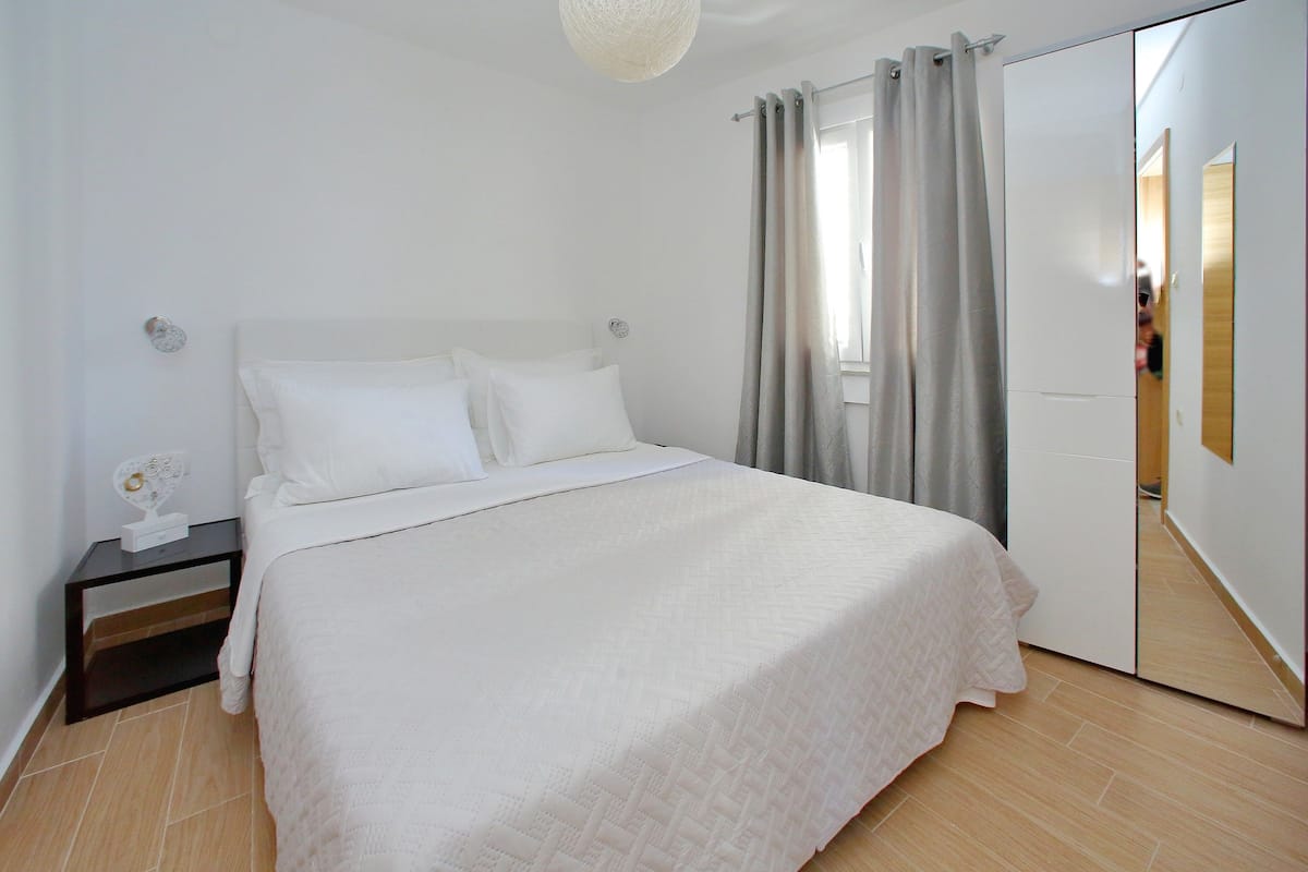 A bedroom with a bed, nightstand, and a mirror.