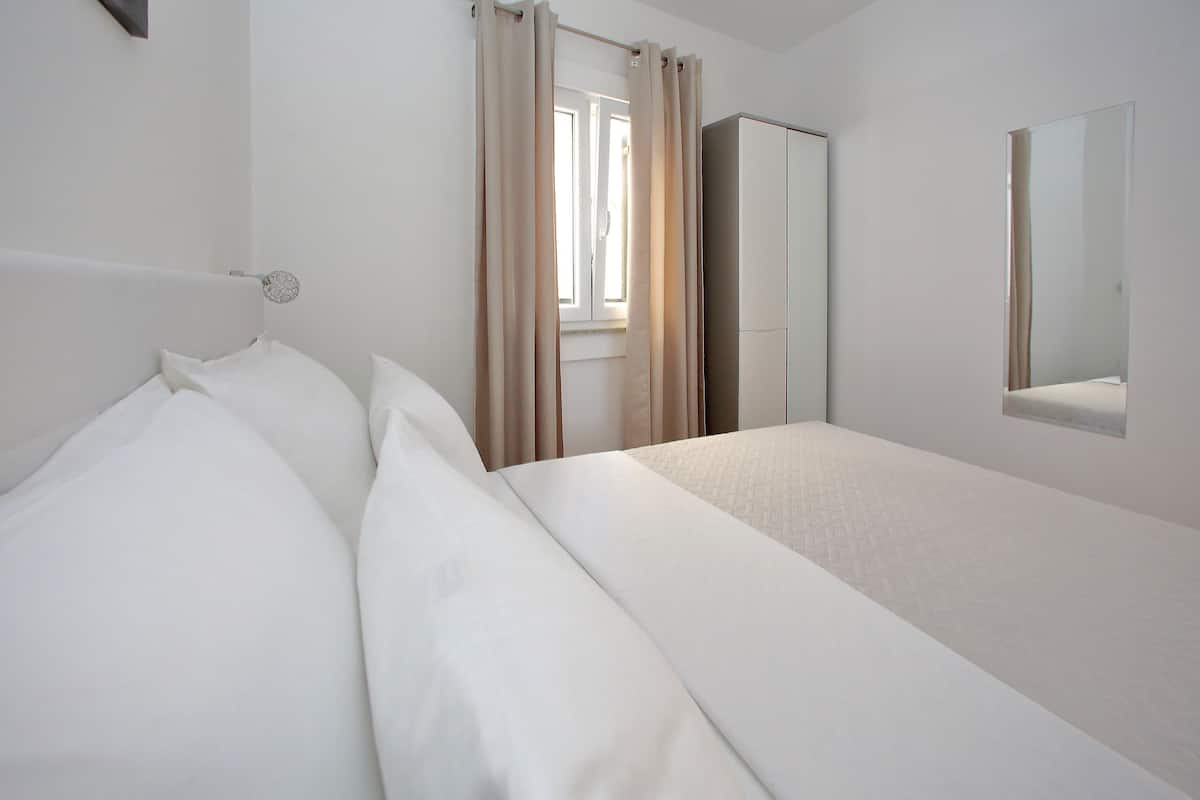 A hotel room with a bed, a wardrobe, and a window with curtains.