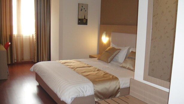 Una camera d'albergo con un letto grande, un comodino e una lampada a parete.