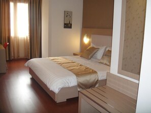 A hotel room with a large bed, a bedside table, and a wall-mounted light. - Sky 2 Hotel (Tirana)