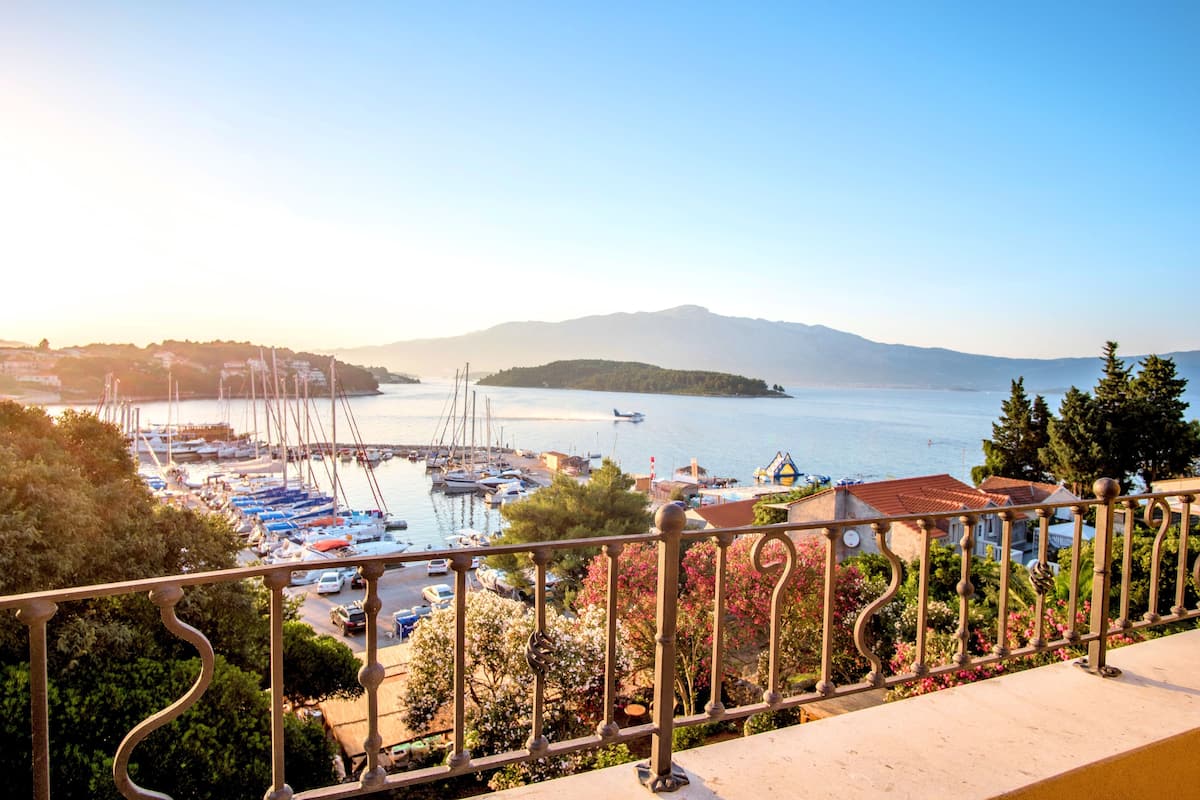 Un port de plaisance avec des bateaux, un ciel dégagé et des montagnes à l’horizon.