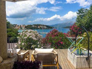A balcony with wicker furniture, a view of a coastal town, and a clear sky. - ECO Aparthotel The Dreamers's Club (Lumbarda)