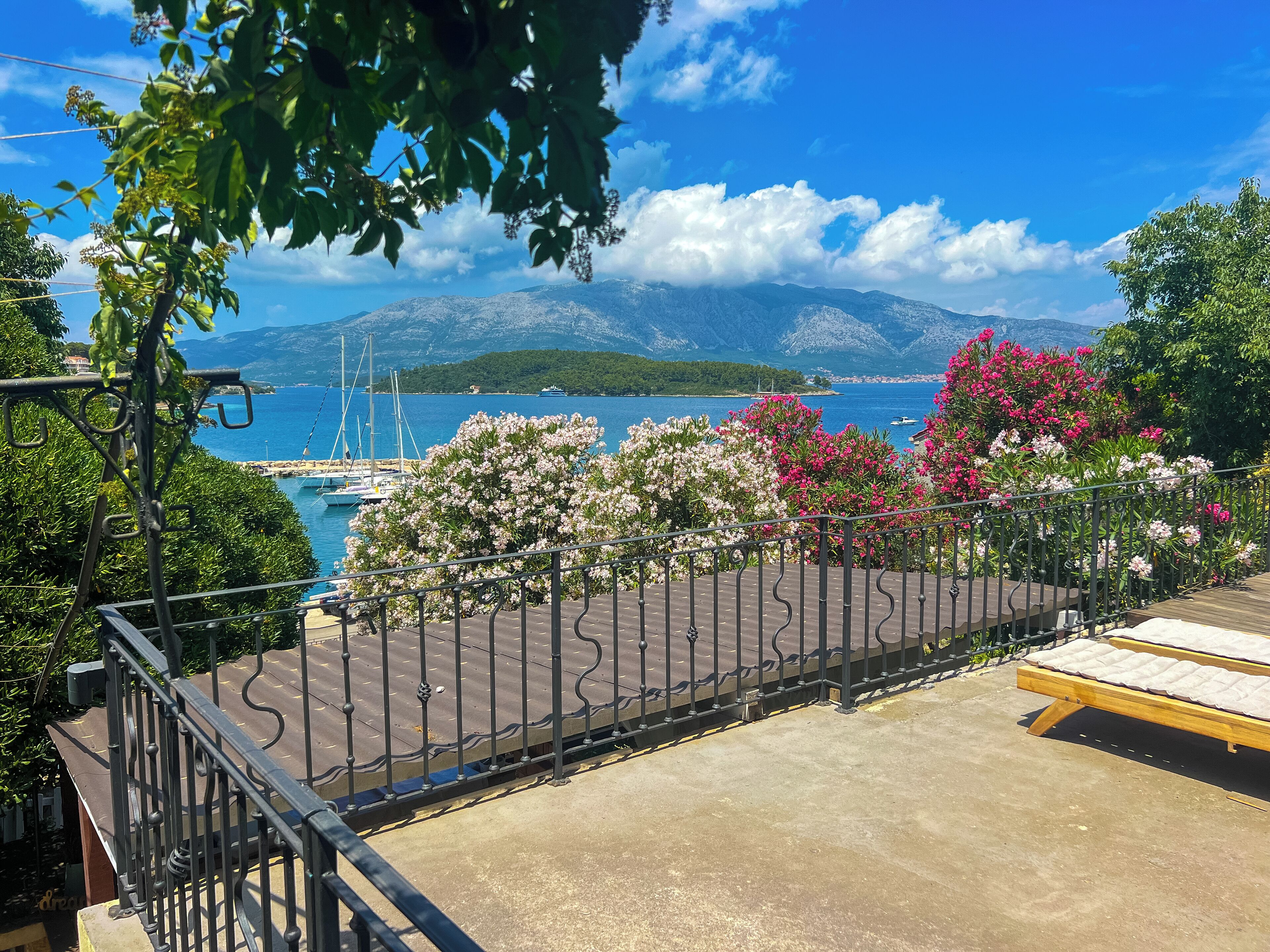Un balcón con vistas a un puerto deportivo, barcos y montañas.