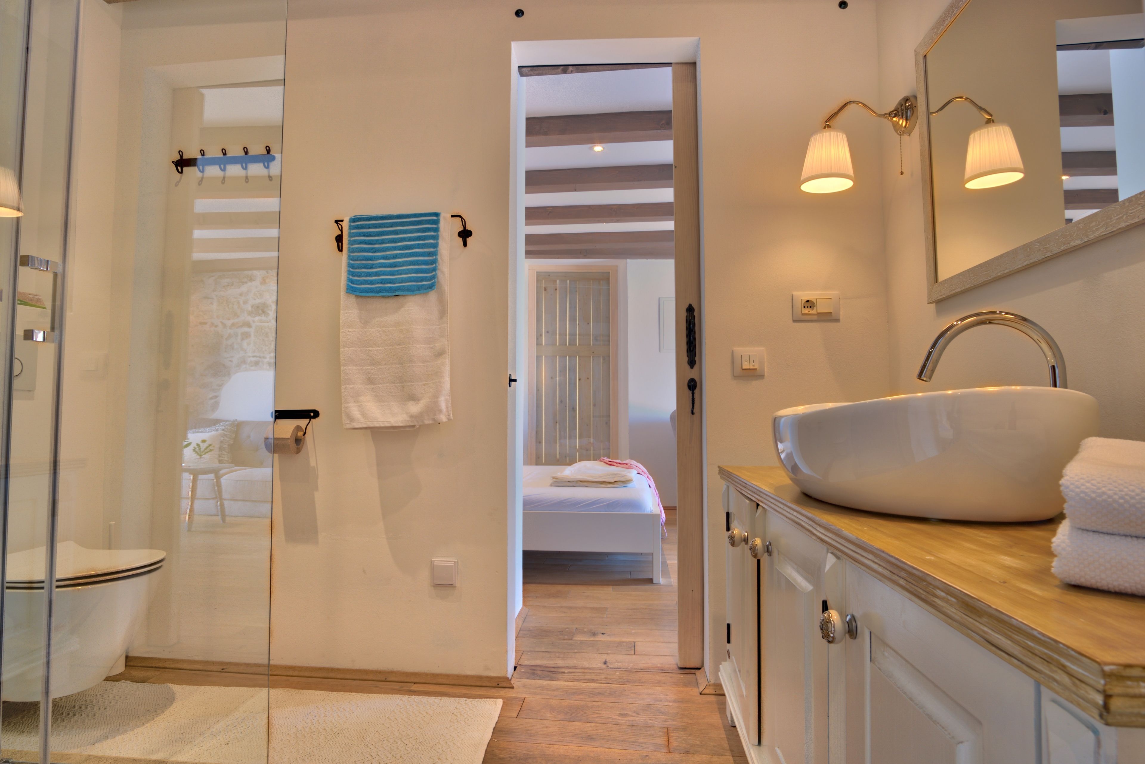 A bathroom with a white sink, a glass shower enclosure, and a wooden vanity.