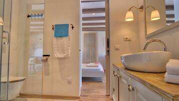 A bathroom with a white sink, a glass shower enclosure, and a wooden vanity.