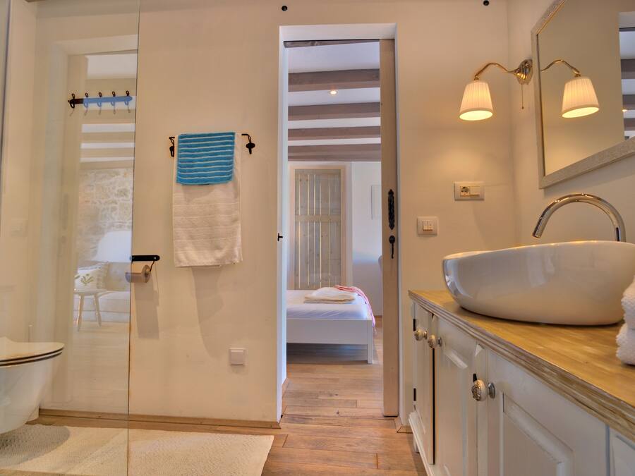 A bathroom with a white sink, a glass shower enclosure, and a wooden vanity.