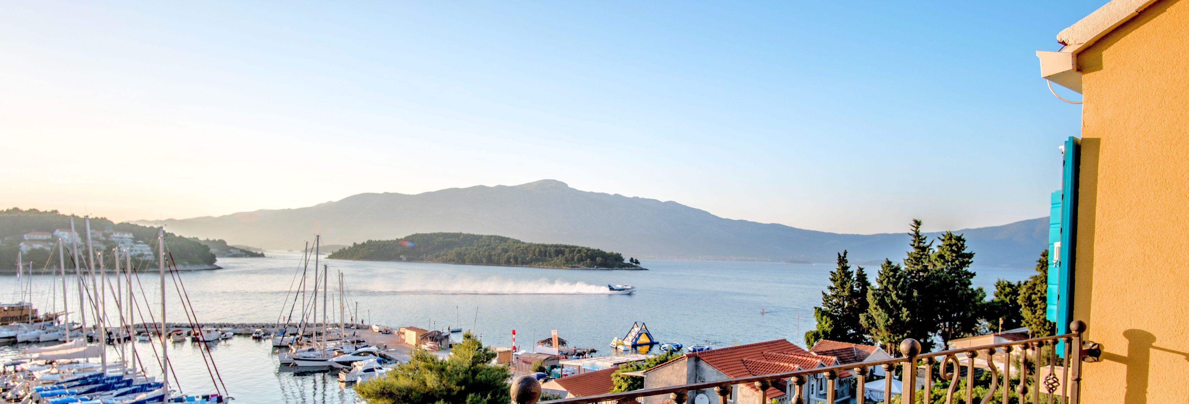 Uma marina com barcos atracados, uma instalação de esportes aquáticos e montanhas ao fundo.