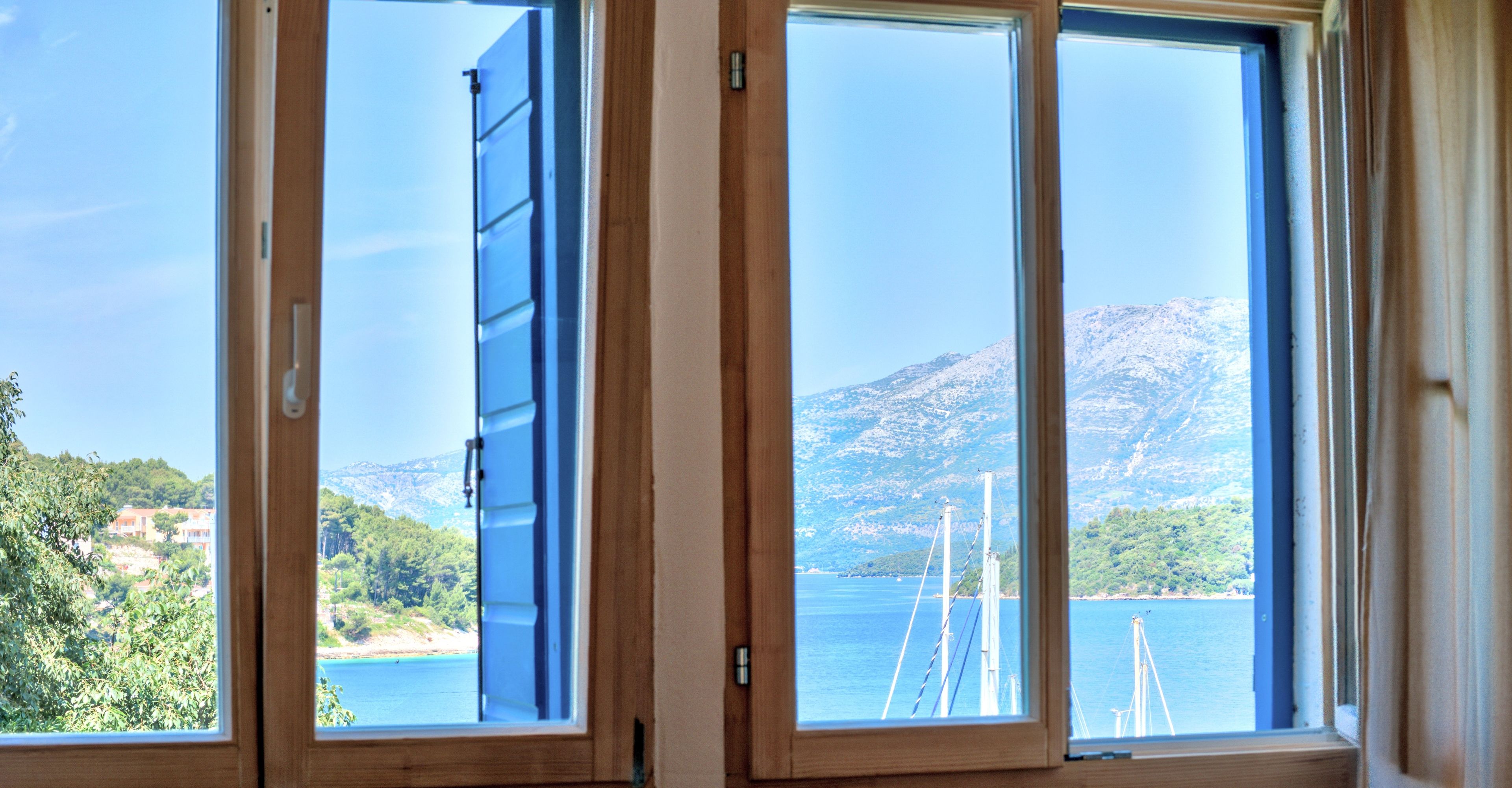 Ein Zimmer mit großem Fenster mit Blick auf ein Gewässer und eine Berglandschaft.