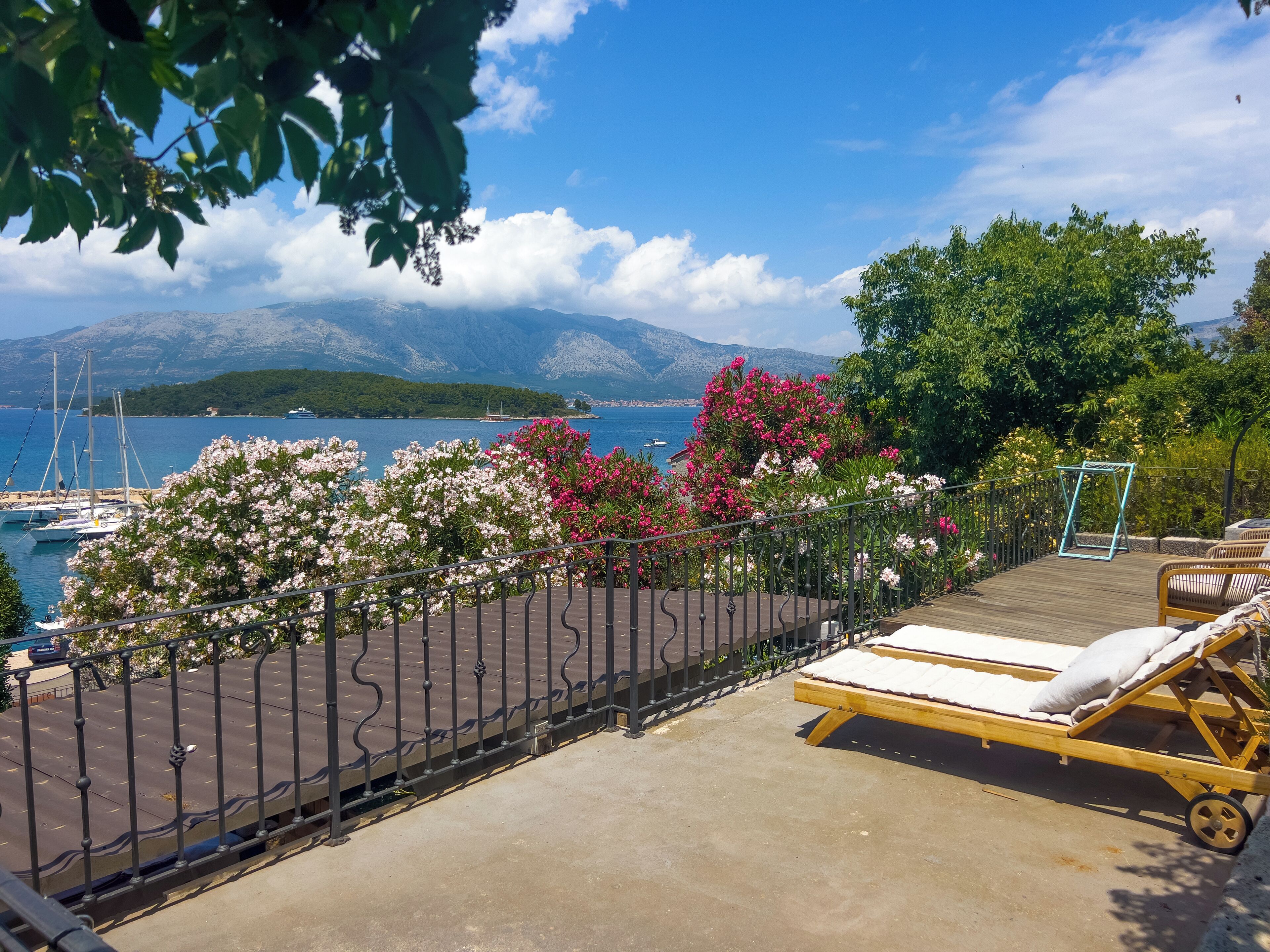 A balcony with a view of the sea, a swing set, and a lounge chair.
