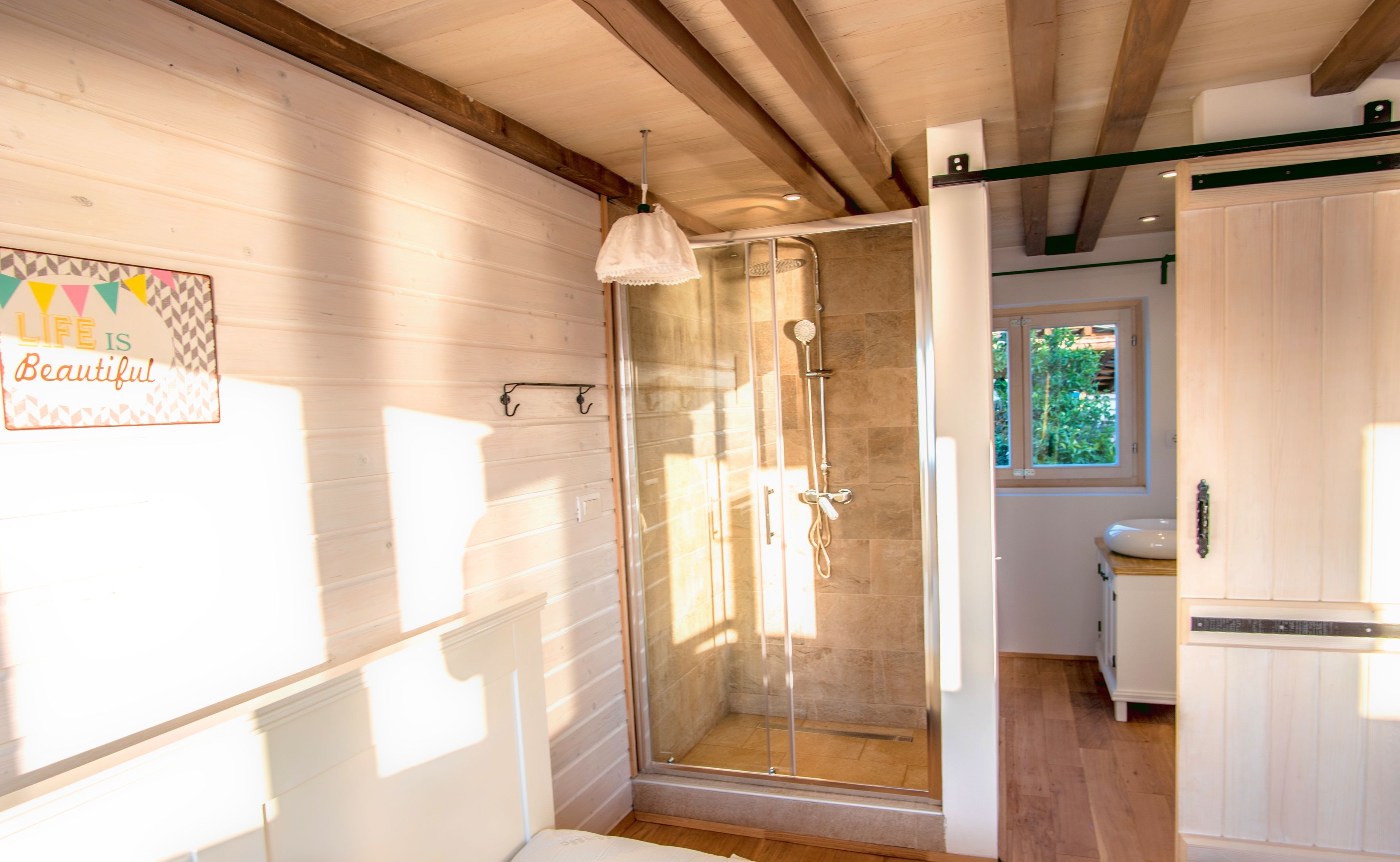Un bagno moderno con cabina doccia in vetro, pareti in legno e una finestra che permette l'illuminazione naturale.