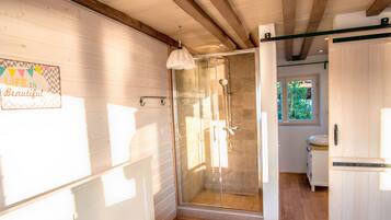 Un bagno moderno con cabina doccia in vetro, pareti in legno e una finestra che permette l'illuminazione naturale.