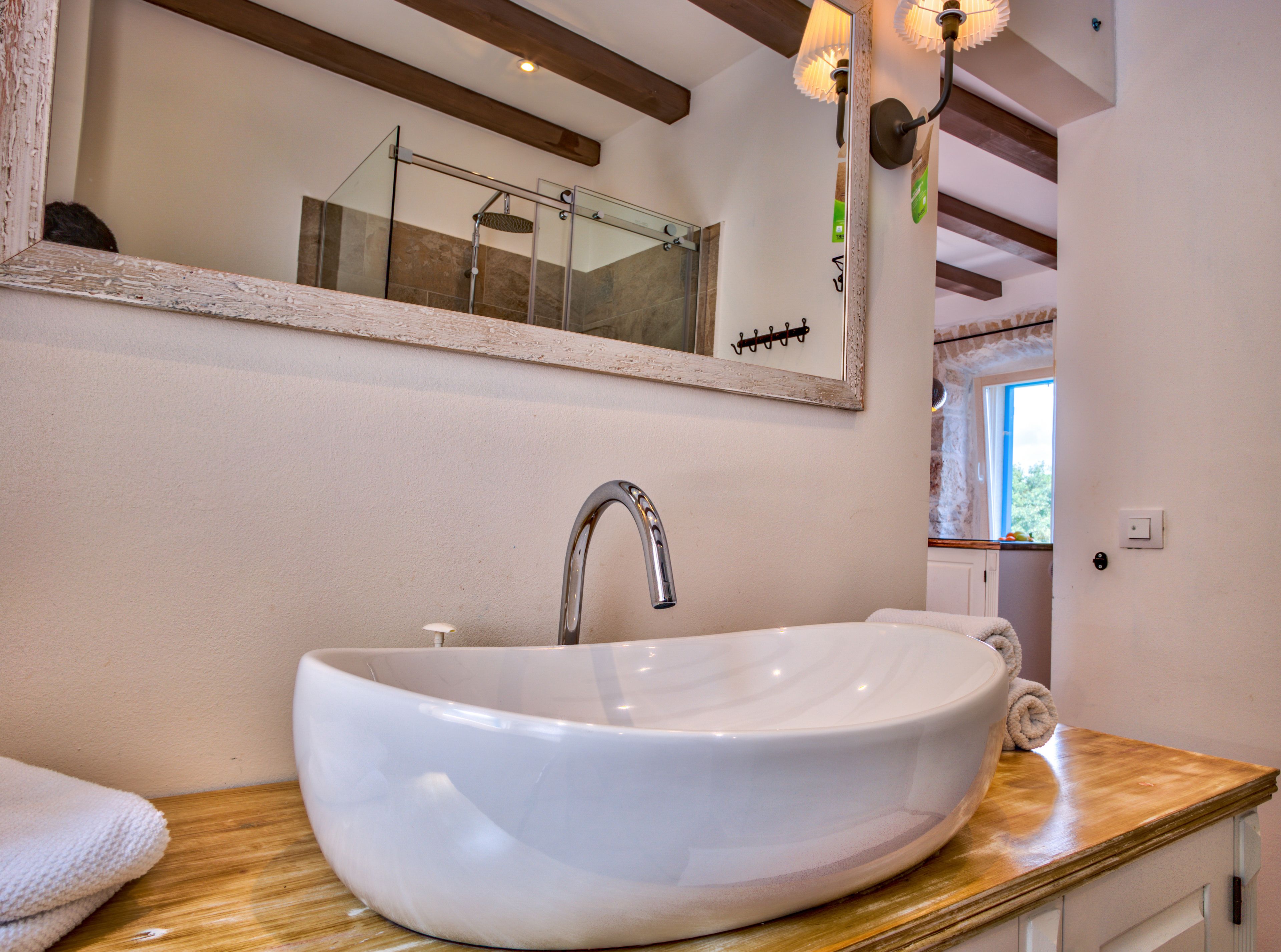 Un baño con un lavamanos grande de color blanco, un espejo y una encimera de madera.