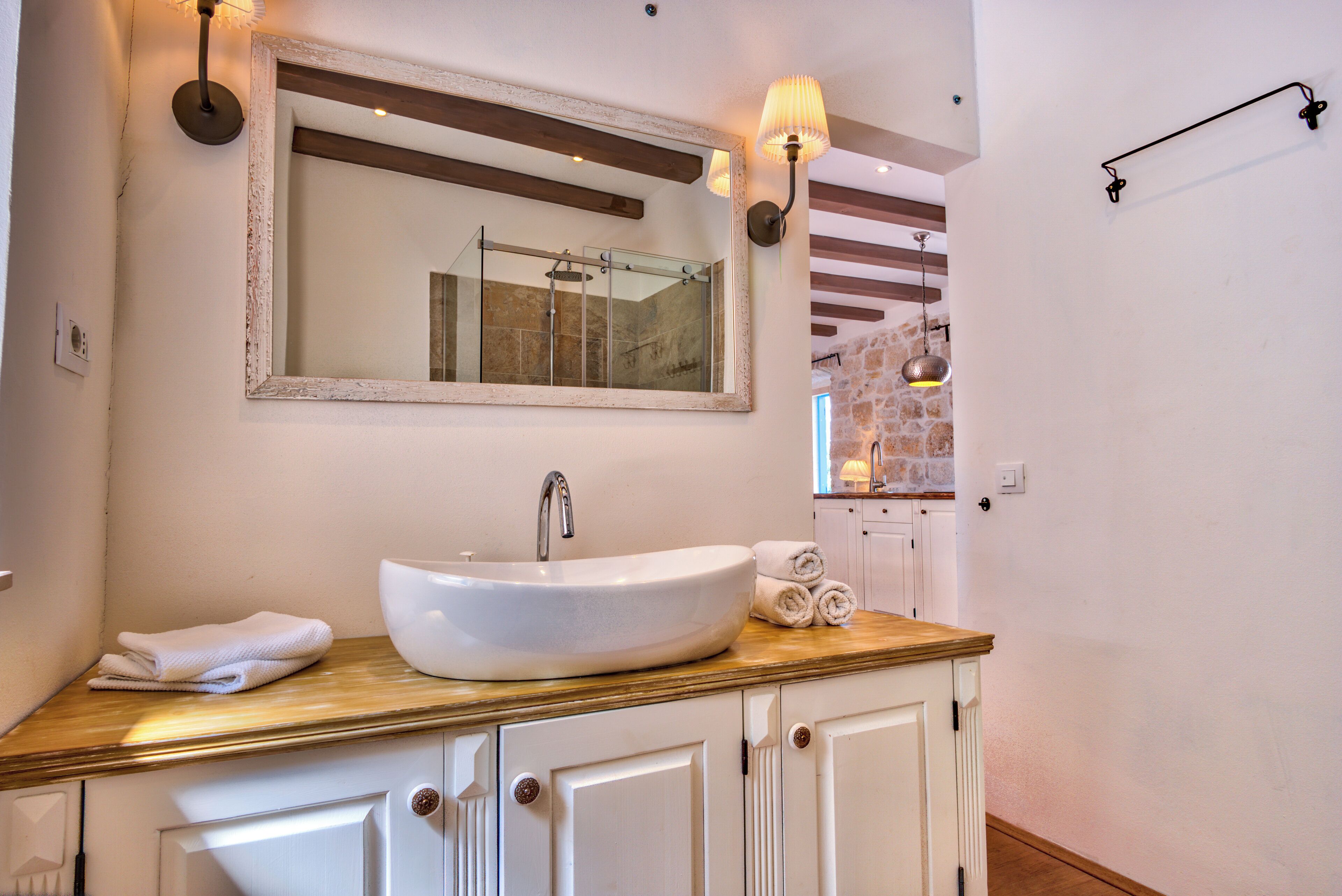 A bathroom with a large mirror, a vessel sink, and a wooden countertop.