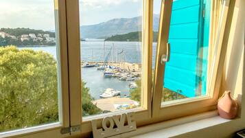 A window with a view of a marina, boats, and a mountainous landscape.