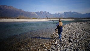 A person fishing by a river with mountains in the background. - Alla Casetta (Cesiomaggiore)