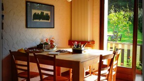 A dining area with a wooden table and chairs, a hanging light fixture, a framed picture on the wall, and a view of the outdoors through a glass door. - Alla Casetta (Cesiomaggiore)