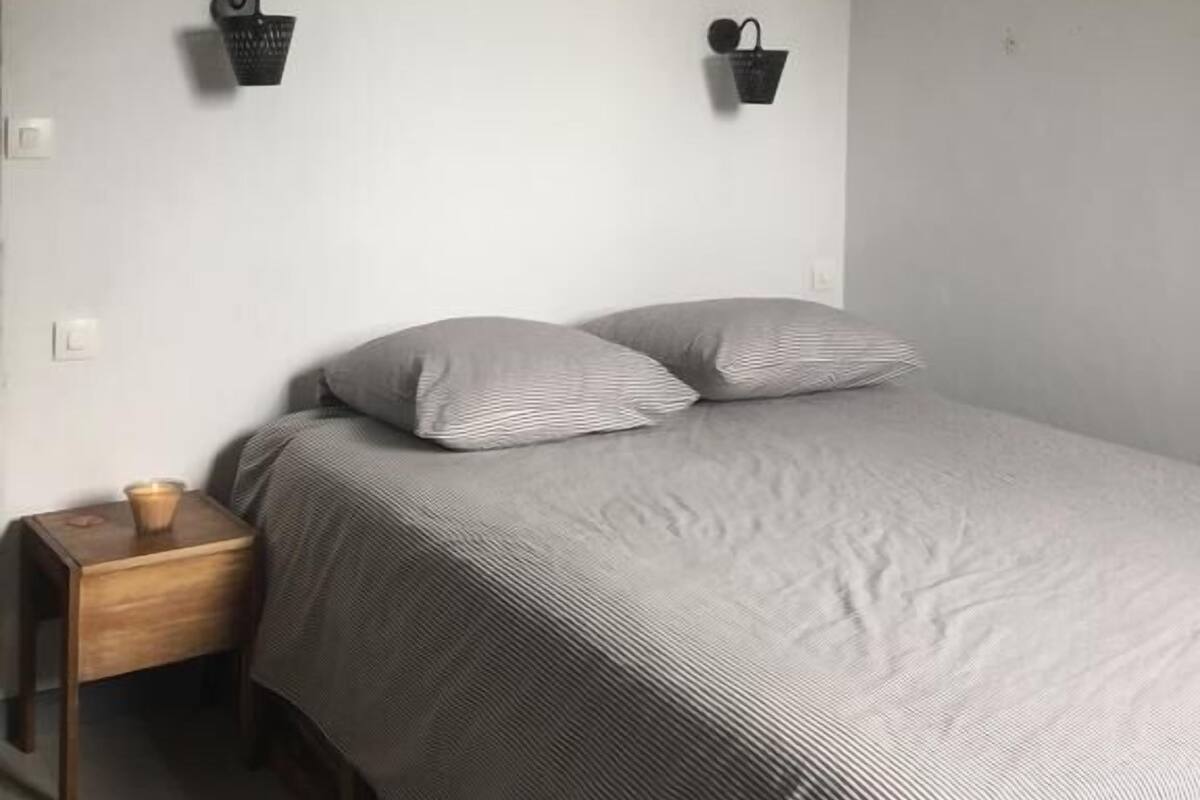 Een slaapkamer met een bed, twee nachtkastjes aan de muur en een houten hoofdbord.