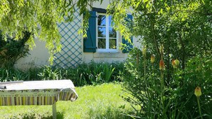 Een huis met een raam, een bankje en een tuin.