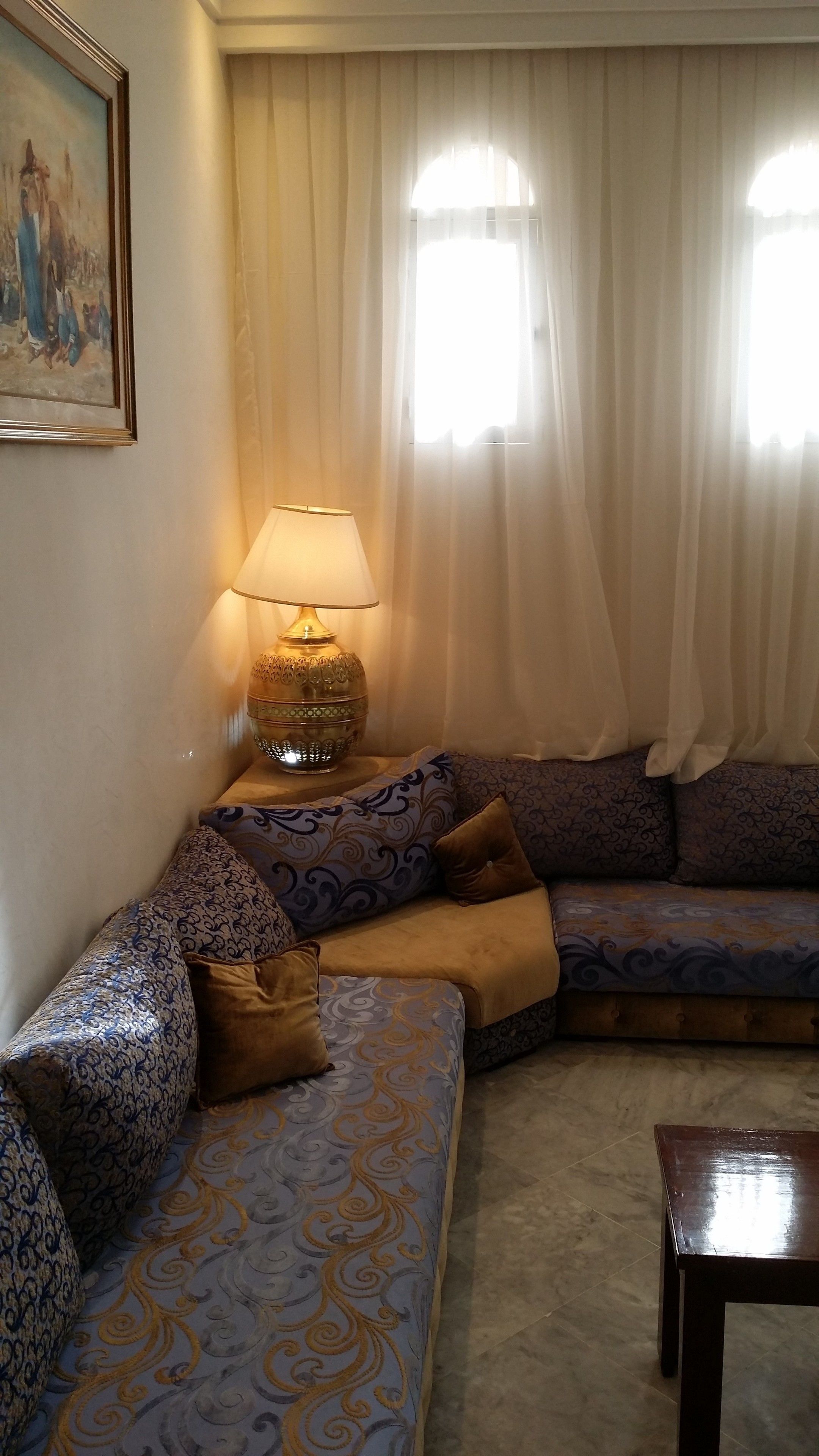 Una sala de estar con un sofá estampado, una lámpara y un cuadro en la pared.