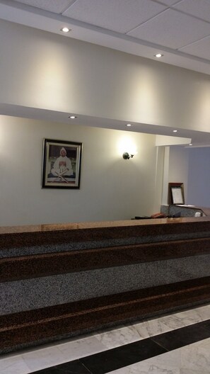 A reception area with a marble staircase, a framed portrait on the wall, and a wall-mounted light fixture. - Sahara Line Hotel (Laayoune)