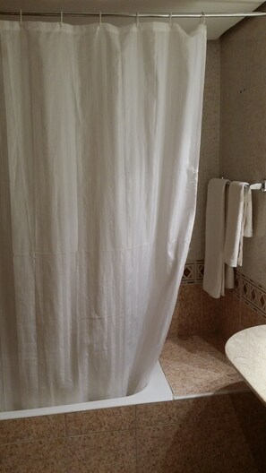 A bathroom with a shower curtain, a bathtub, and a towel rack with towels. - Sahara Line Hotel (Laayoune)