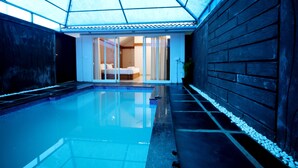 A swimming pool with a glass ceiling, a wooden wall, and a door leading to a room with a bed. - Wayanad Ranches Resorts (Vythiri)