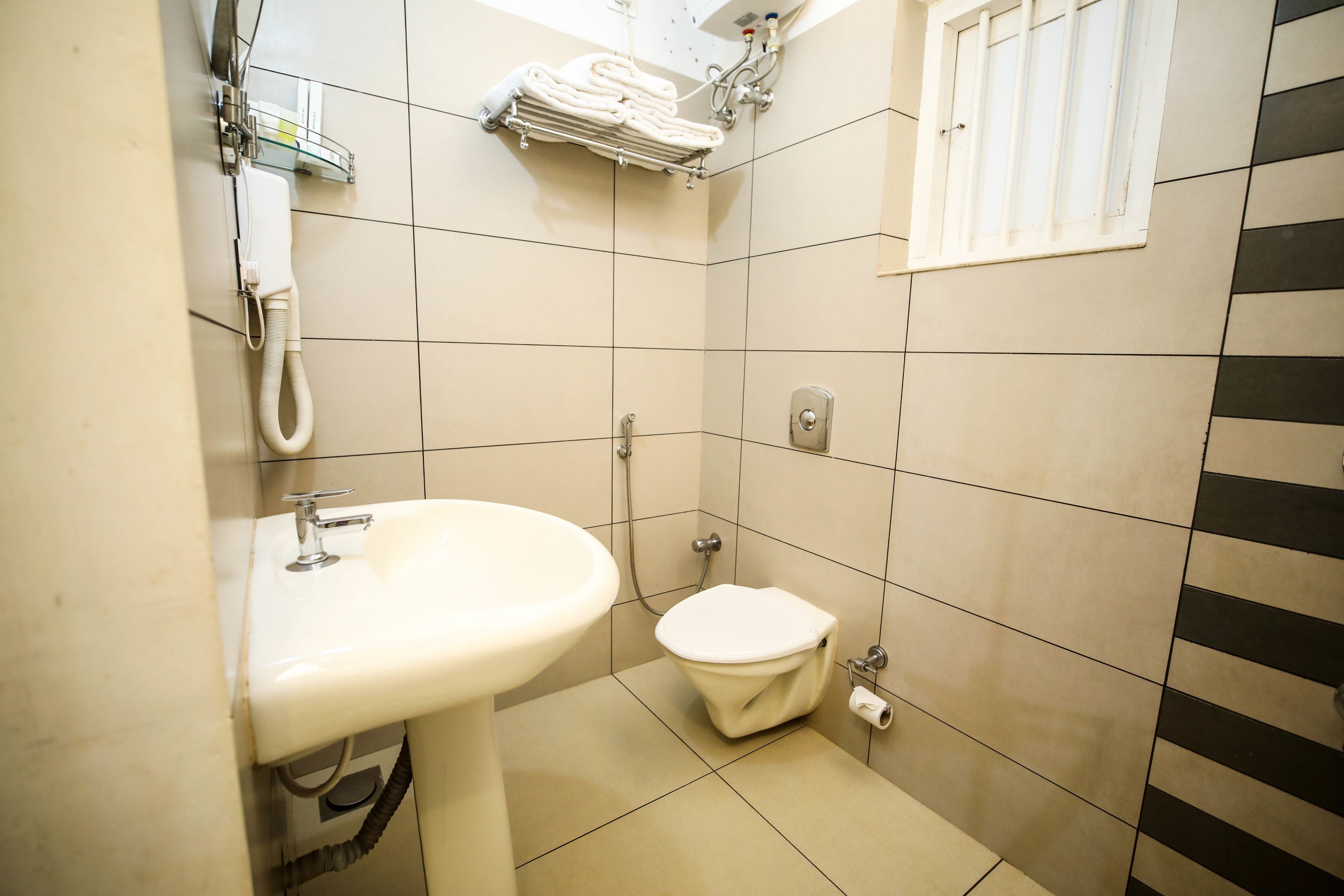 Een kleine badkamer met een wastafel, toilet en een handdoekhouder.