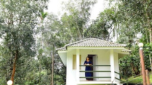 A small, elevated wooden structure with a tiled roof, surrounded by dense greenery. - Wayanad Ranches Resorts (Vythiri)