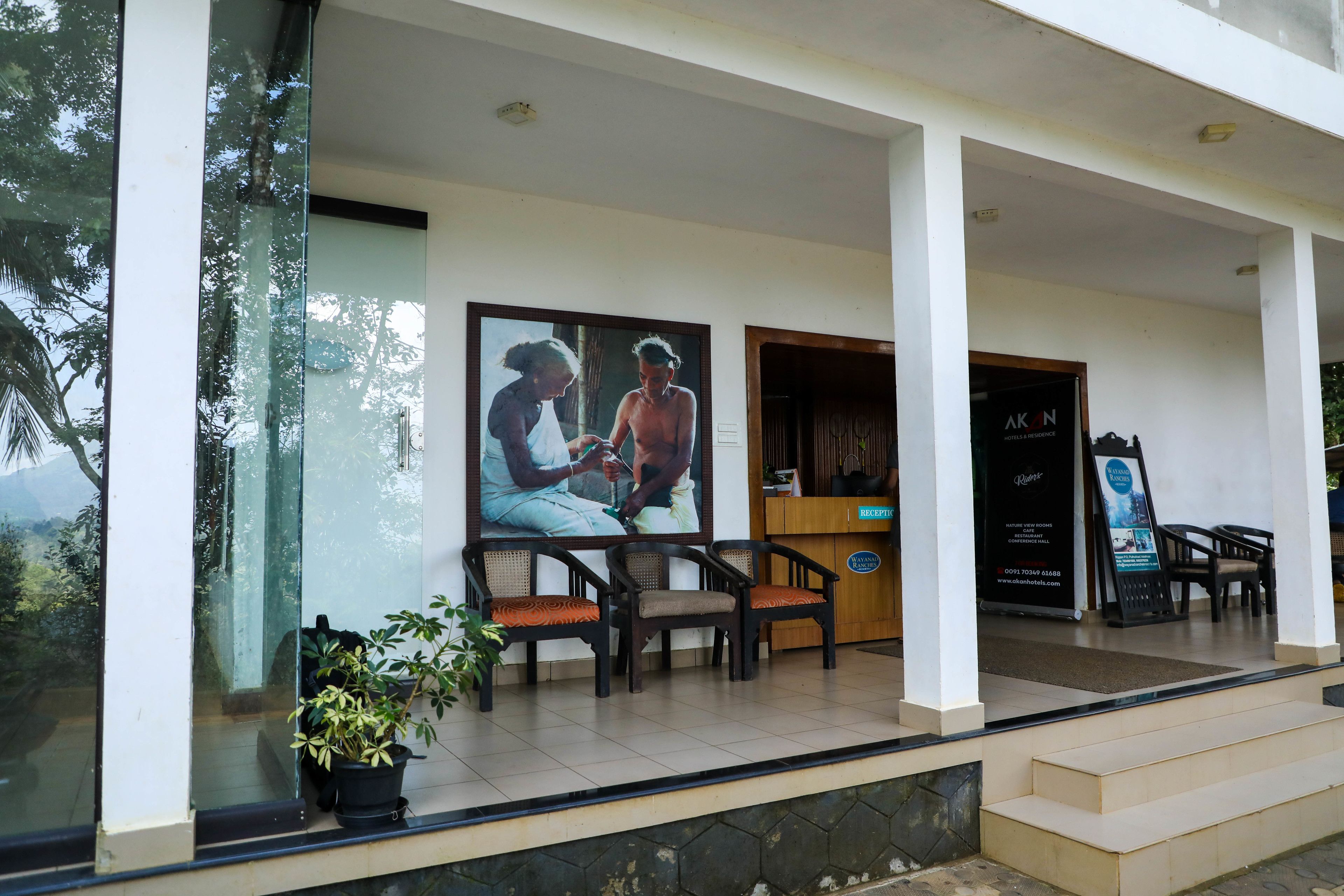 A hotel entrance with a reception desk, seating area, and a large poster on the wall.
