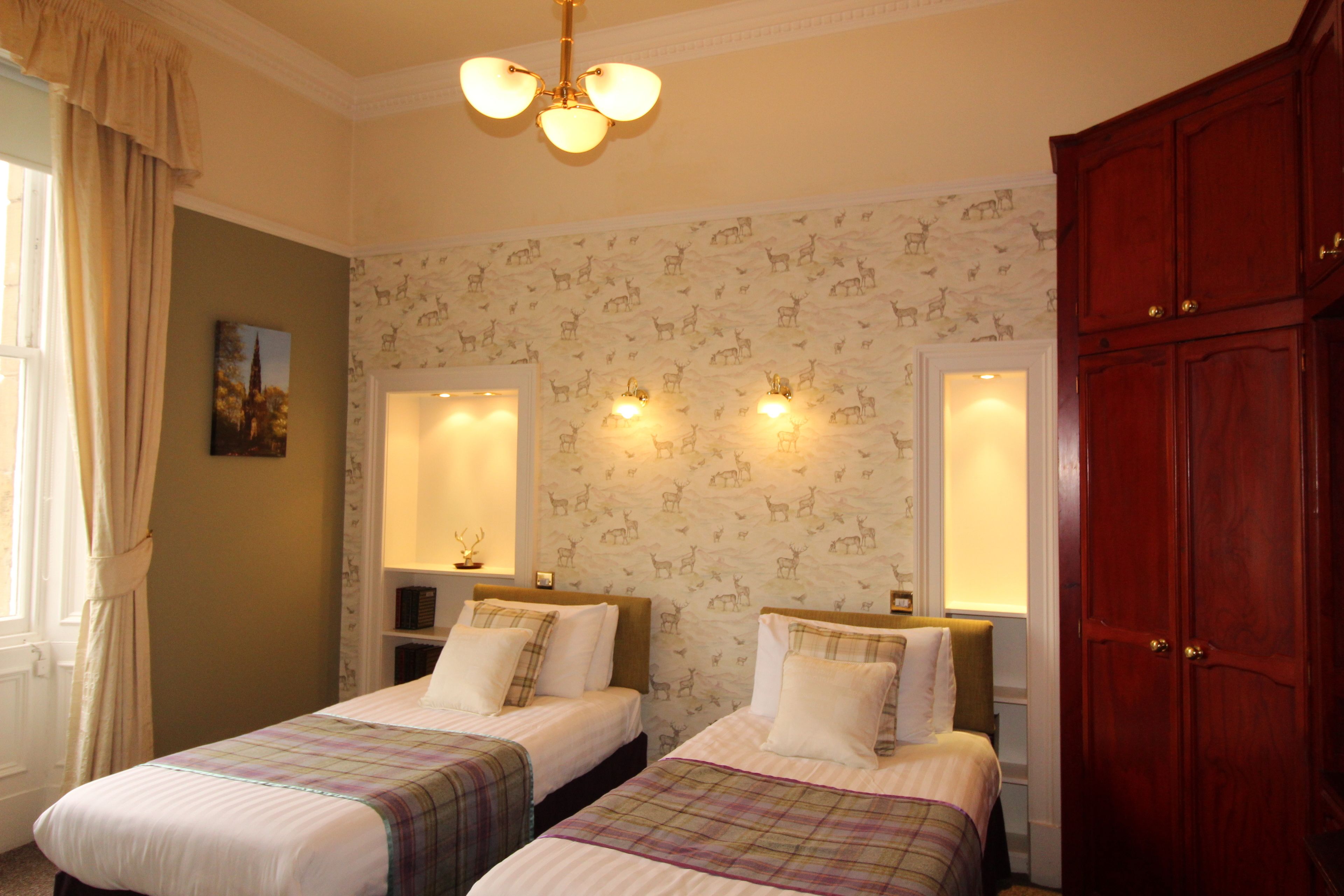 Une chambre d’hôtel avec deux lits, une armoire en bois et un mur décoratif orné de motifs animaliers.