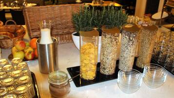 A buffet table with various food items and containers, including a metal pitcher, jars, and bowls.