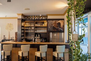 A bar area with a long counter, three bar stools, shelves with glasses and bottles, and a refrigerator. - Check Inn Hotel (Merseburg)