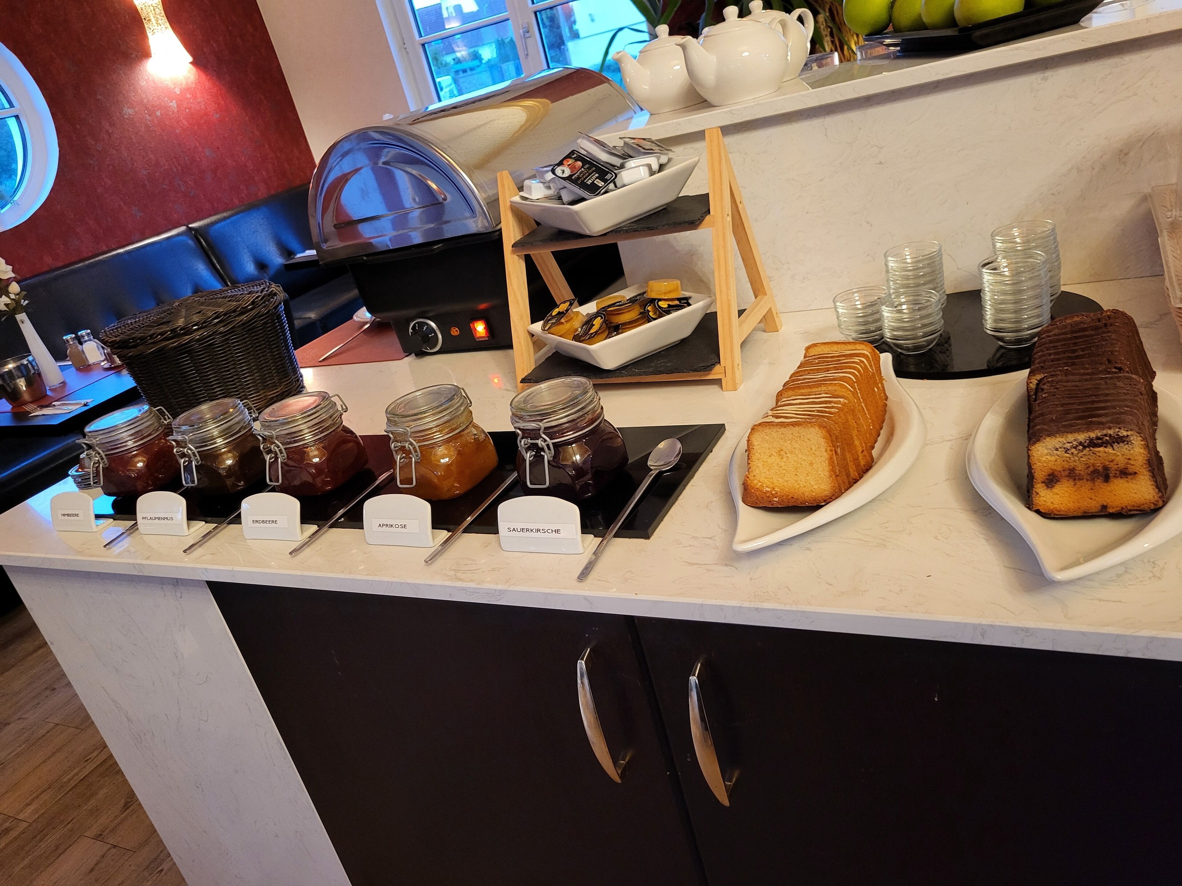 Un bufé de desayuno con diversas opciones de untables, una máquina de café y una selección de pasteles.