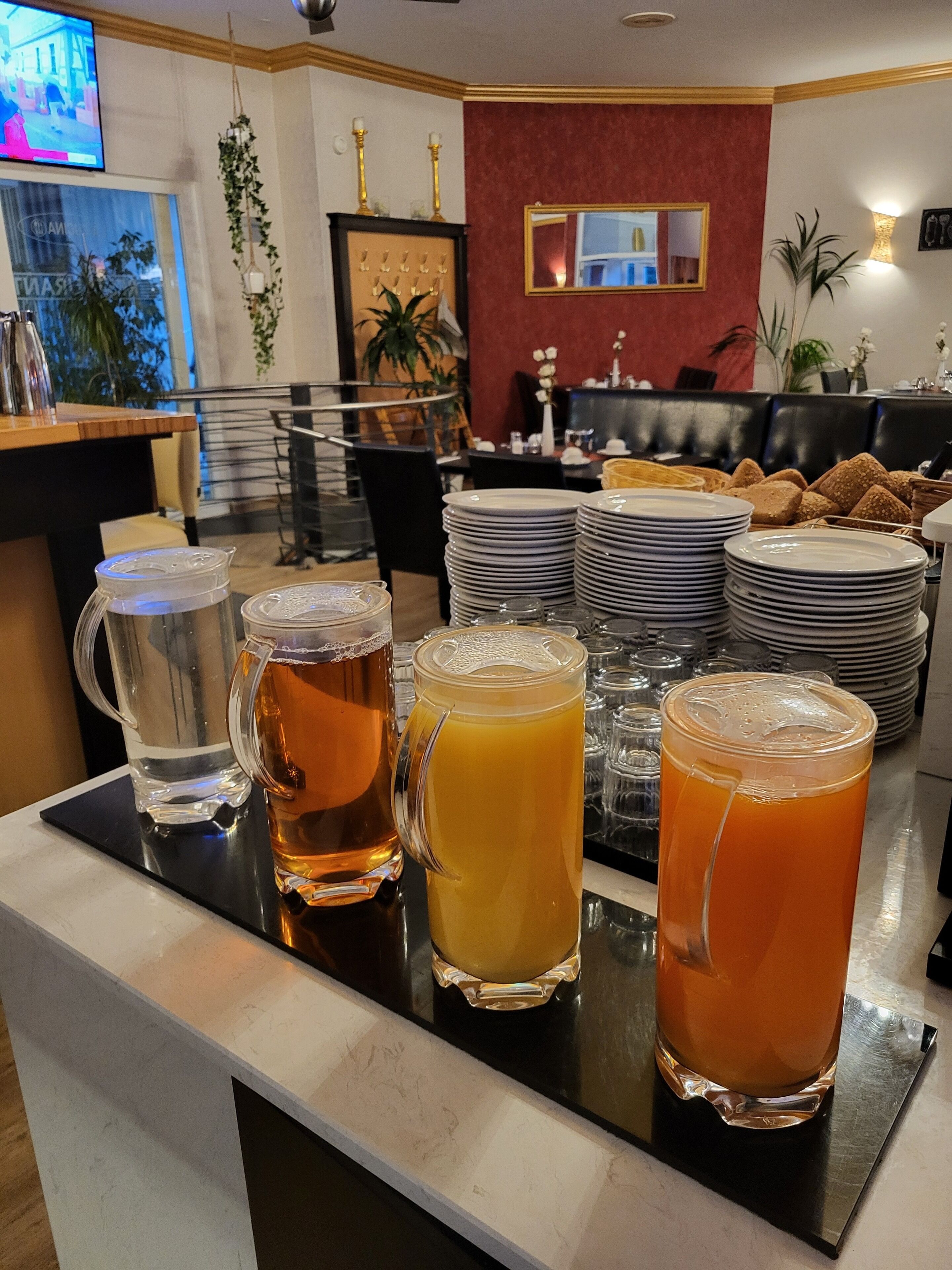 Un espace bar avec des assiettes empilées, un téléviseur et un choix varié de boissons.