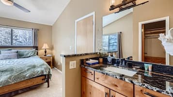 A bedroom with a bed, bedside table, lamp, and a large window.