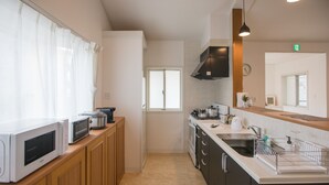 A modern kitchen with a microwave, toaster, stove, sink, and cabinets. - Villa Del Oro Oceanside (Chatan)