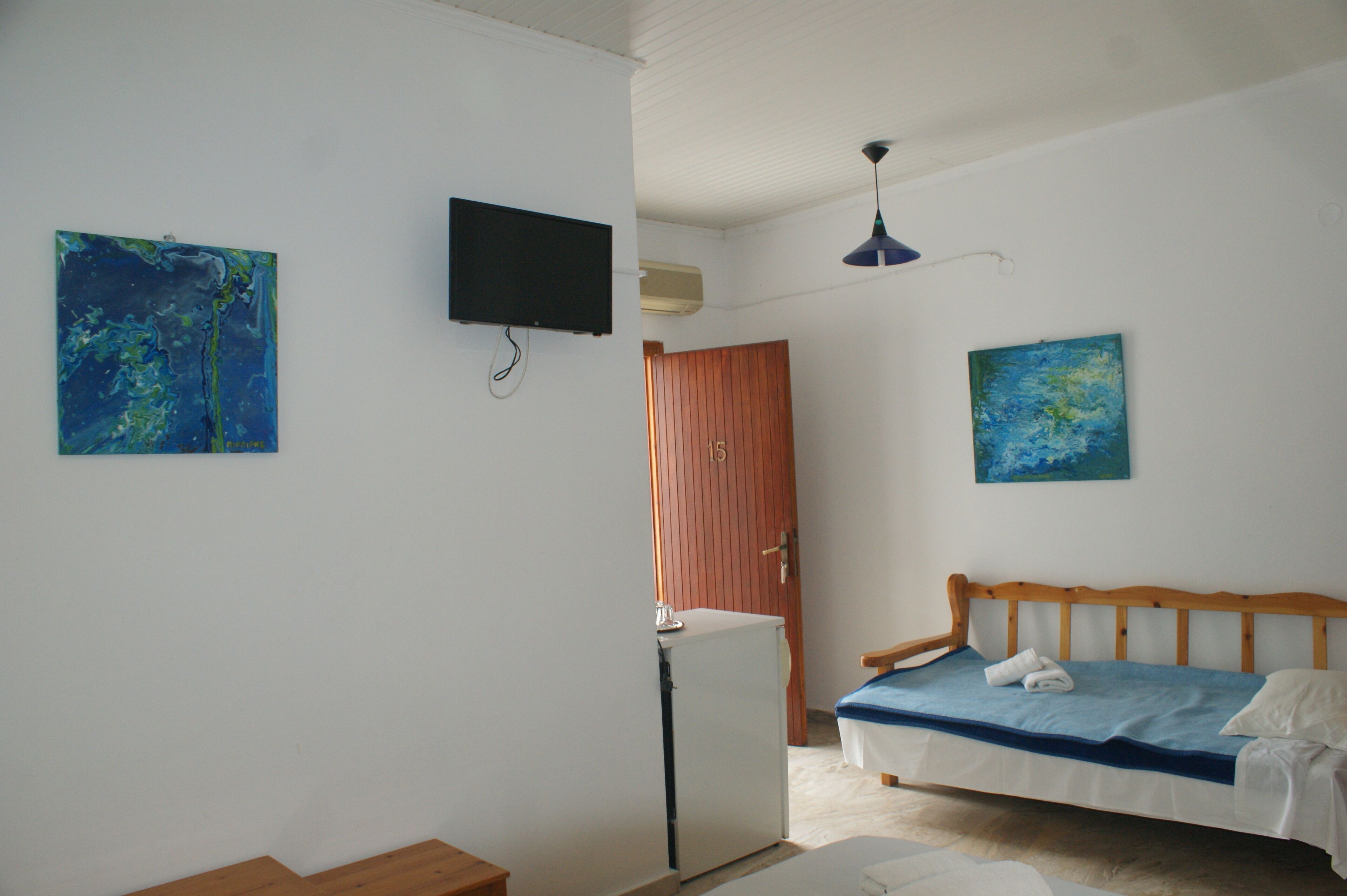 Una habitación con una cama, un televisor y dos cuadros en las paredes.