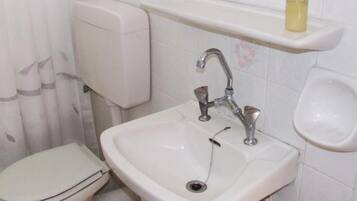 Ein Badezimmer mit einem weißen Waschbecken, einer Toilette und einem Regal darüber.