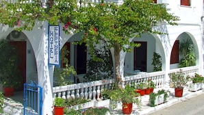 Un bâtiment blanc avec une enseigne indiquant « HÔTEL ELEFTHERIA » et un balcon orné de plantes en pot.