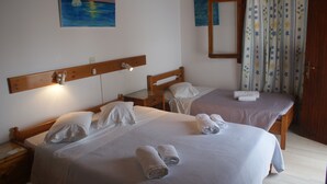Une chambre d’hôtel avec deux lits, chacun agrémenté de serviettes soigneusement pliées et d’une tête de lit en bois.
