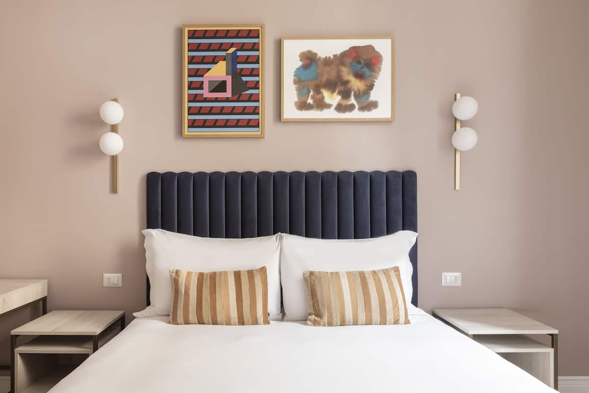 A neatly arranged hotel room with a large bed, two bedside tables, and a headboard with vertical panels.